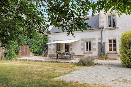 A stone house with a patio, outdoor seating, and a covered area.