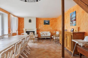 Un comedor con una mesa larga y sillas, una chimenea y un cuadro en la pared.