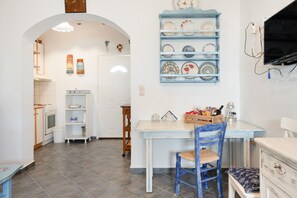 Una cocina con estufa blanca, mesa de madera y silla azul.