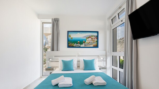 Une chambre d’hôtel avec un lit, un tableau, une télévision et une fenêtre.
