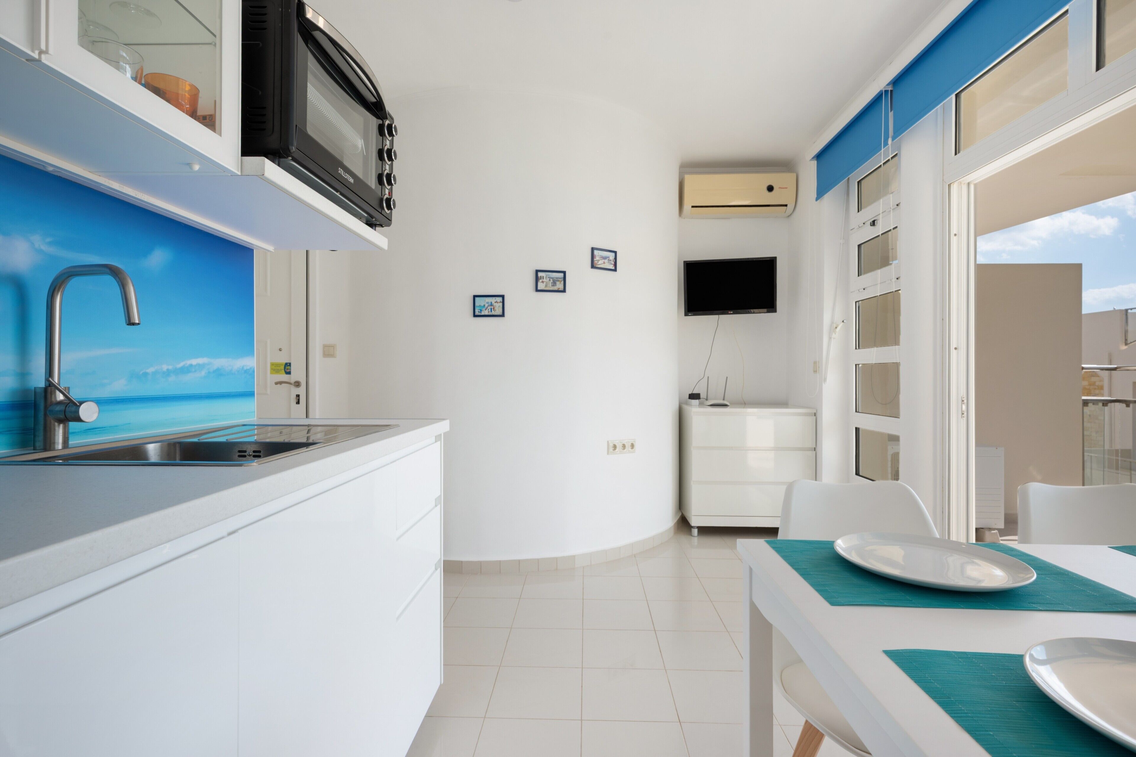 A modern kitchen with a built-in microwave, a stainless steel sink, and a dining area with a table and chairs.