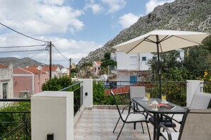 A balcony with a table, chairs, and an umbrella.