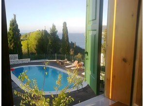 Ein Pool mit Blick auf Bäume und Hügel, ein Tisch mit Stühlen und eine grüne Tür.
