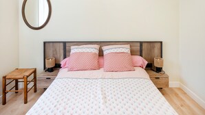 Una camera da letto con un letto, due comodini, uno sgabello e uno specchio fissato alla parete, oltre a una testiera in legno.