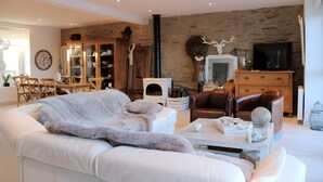 Ein Wohnzimmer mit Sofa, Couchtisch, Kamin, Fernseher und einer Steinwand.