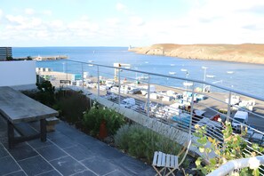 A coastal view with a marina, boats, and a distant lighthouse. - Harborfront Seaside House with Port View (Le Conquet)