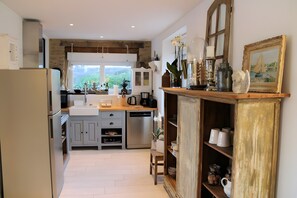 A kitchen with a wooden countertop, a sink, and a dishwasher. There is a cabinet with glass doors and a shelf with jars. - Harborfront Seaside House with Port View (Le Conquet)