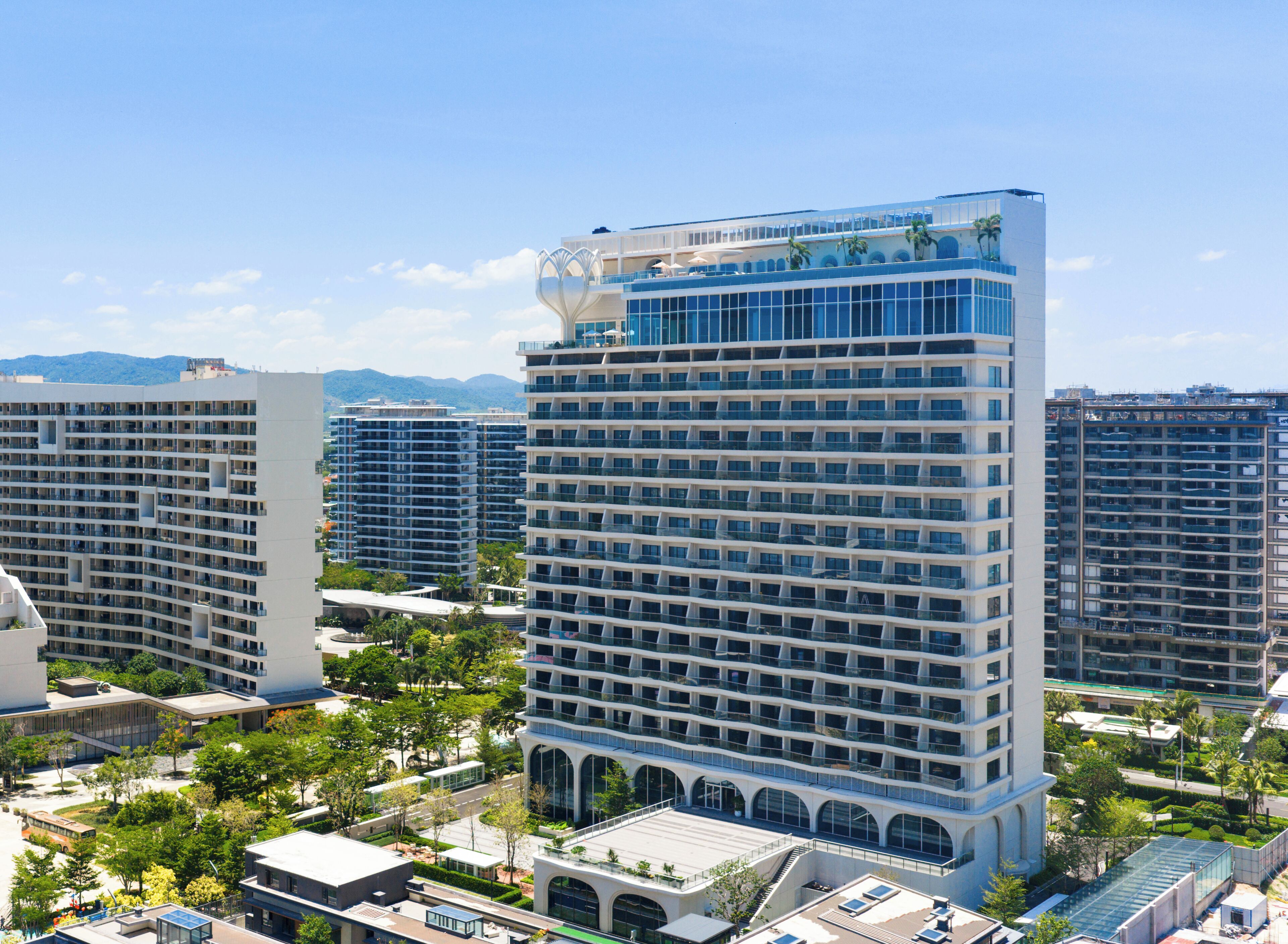 A high-rise hotel with multiple balconies, a rooftop terrace, and a view of the surrounding cityscape.