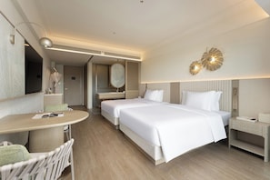 A hotel room with two beds, a sitting area with a table and chairs, a mirror, and a bedside table with a lamp. - LAYARDA HOTEL SANYA HAITANG BAY (Sanya)