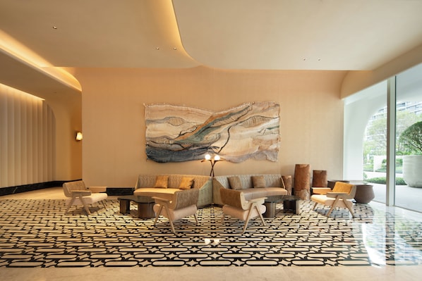 A modern lobby with a large abstract painting, a patterned carpet, and contemporary furniture.