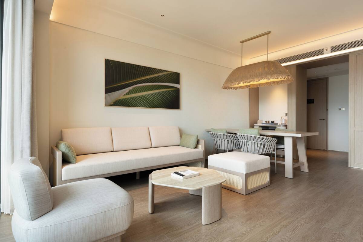 A modern living room with a sofa, a coffee table, and a dining area.