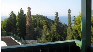 A view from a balcony with a stone wall, a metal railing, and a variety of trees. - Apartment 'Villa Milia - Sea View' with Sea View, Wi-Fi and Air Conditioning (Lefkada)