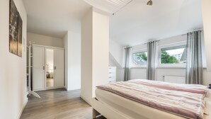 Un dormitori amb un llit gran, un armari i una finestra amb cortines.