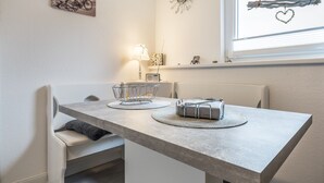 A dining area with a table, chairs, a lamp, and a wall clock. - Apartment “Seepferdchen” with Wi-Fi (Cuxhaven)