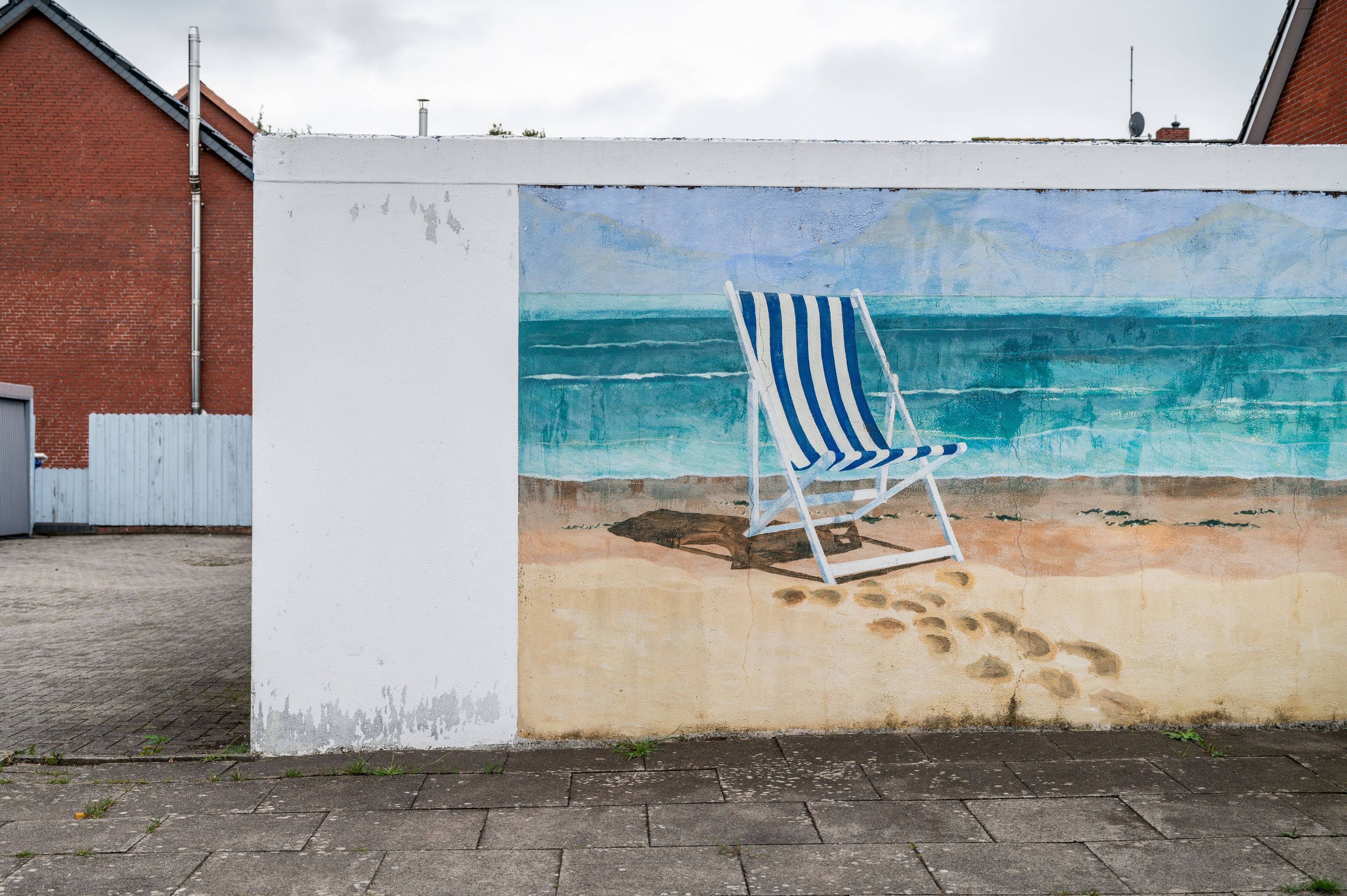 Une fresque murale représentant une scène de plage avec une chaise de plage à rayures.