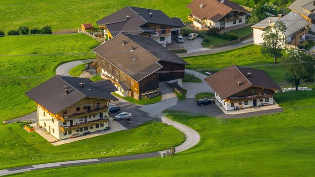 A residential area with multiple houses, a winding driveway, and a grassy landscape.
