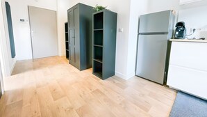 A modern kitchen with a built-in refrigerator, a coffee machine, and a small plant on the counter. - Premium Studio – Modern, Functional with Wi-Fi (Saint-Martin-d'Hères)