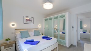 Een slaapkamer met een bed, nachtkastjes, een spiegel en een kledingkast.