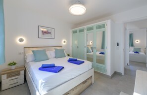 A bedroom with a bed, bedside tables, a mirror, and a wardrobe. - 'Puerto Chico K' with Sea View, Shared Pool and Wi-Fi (Playa Blanca)