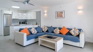 Een moderne woonkamer met een bank, salontafel en een keuken op de achtergrond.