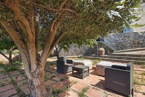 Un espace extérieur aménagé en terrasse, avec des meubles en osier, un mur en pierre et un escalier.
