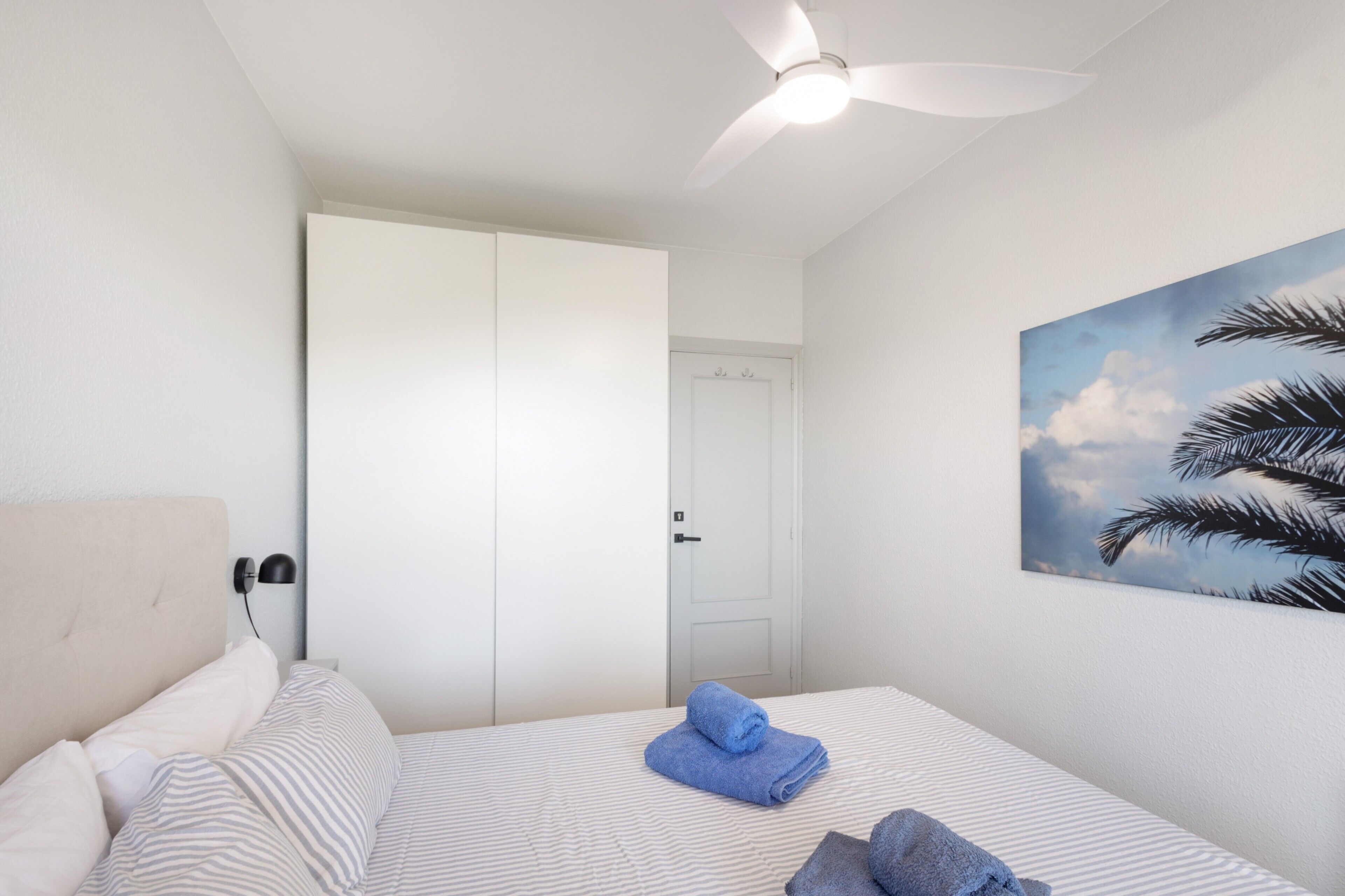 A bedroom with a bed, a ceiling fan, a door, and a wall-mounted painting.. Holiday Home 'Between Forest and Sea' with Sea View, Private Terrace and Wi-Fi
