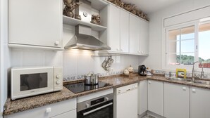 Eine moderne Küche mit weißen Schränken, einer Mikrowelle, einem Herd, einem Backofen und einem Fenster mit Blick.