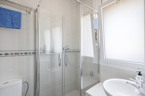 A bathroom with a glass-enclosed shower, a white sink, and a blue towel on a rack. - Holiday Home 'Between Forest and Sea' with Sea View, Private Terrace and Wi-Fi (Canyelles)