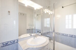 Une salle de bain avec un lavabo, un miroir, une douche et des murs carrelés.