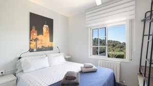 Ein Schlafzimmer mit Bett, Fenster mit Blick, einem Gemälde an der Wand und einer Heizung.