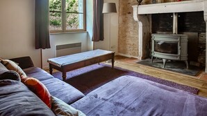 A room with a bed, a bench, a fireplace, and a window. - Holiday Home "Gîte De Chez Chenon" with Private Garden (Saint-Sulpice-de-Ruffec)