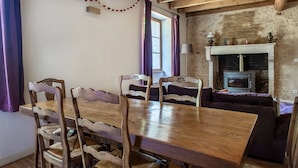A dining area with a wooden table and chairs, a fireplace, and a stone wall. - Holiday Home "Gîte De Chez Chenon" with Private Garden (Saint-Sulpice-de-Ruffec)