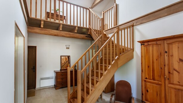 A multi-level wooden staircase with a loft bedroom above, a large wooden cabinet, and a brown leather chair. - Holiday Home "Gîte De Chez Chenon" with Private Garden (Saint-Sulpice-de-Ruffec)