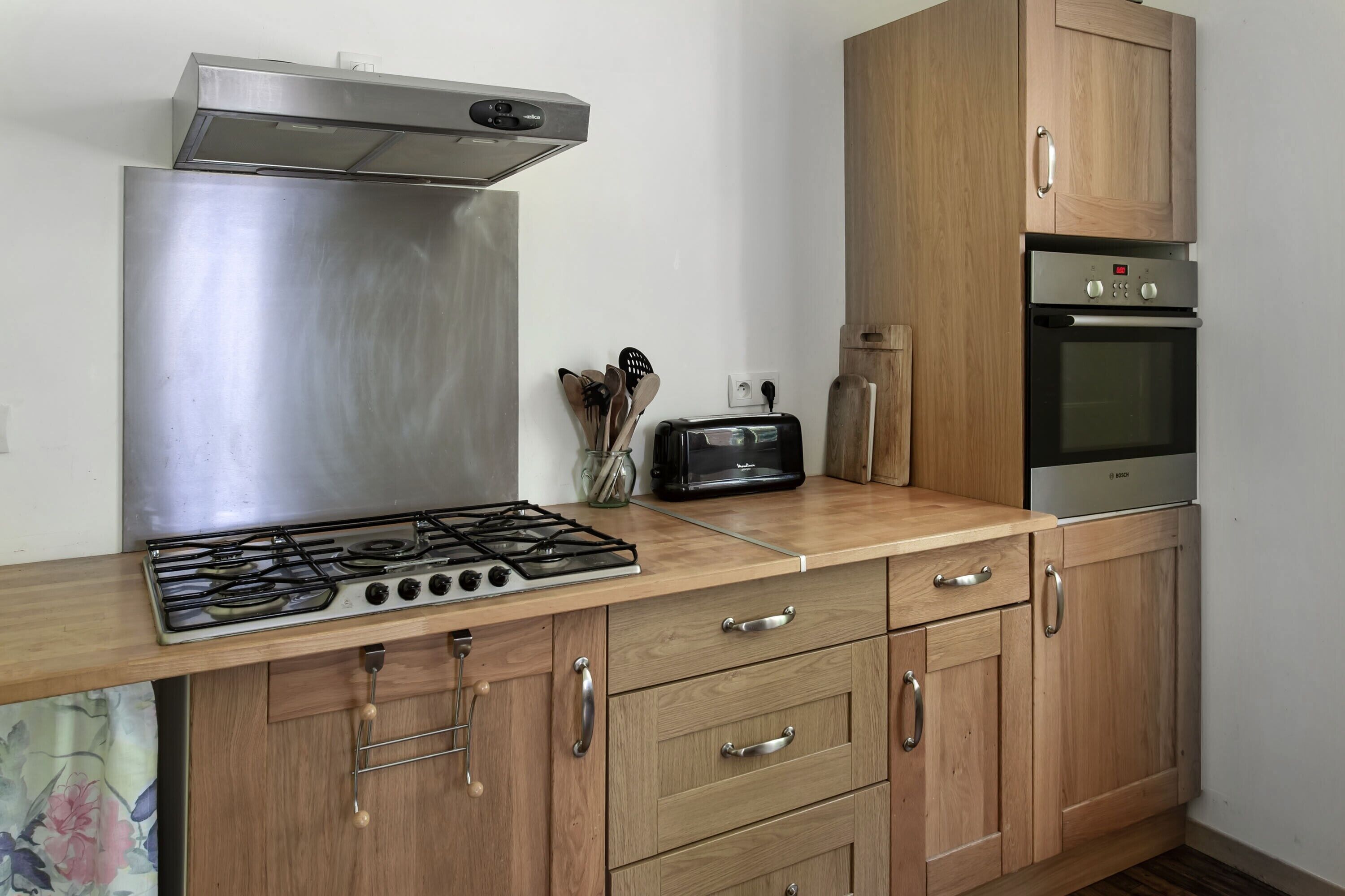 Une cuisine équipée d’une cuisinière en acier inoxydable, de meubles de rangement en bois, d’un grille-pain et d’un four.