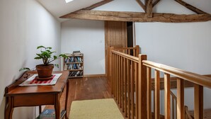A room with a wooden staircase, a bookshelf, a table with a plant, and a window. - Holiday Home "Gîte De Chez Chenon" with Private Garden (Saint-Sulpice-de-Ruffec)