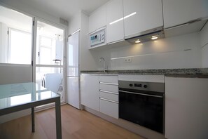 Een moderne keuken met witte kasten, een inbouwoven en een glazen tafel.