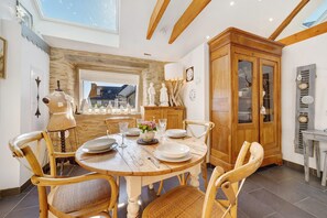 Un comedor con una mesa redonda de madera, cuatro sillas y un armario con puertas de vidrio.