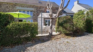 A stone building with a patio area, outdoor seating, and a tree in the foreground.