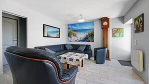 A living room with a sofa, a coffee table, a clock, and artwork on the walls.