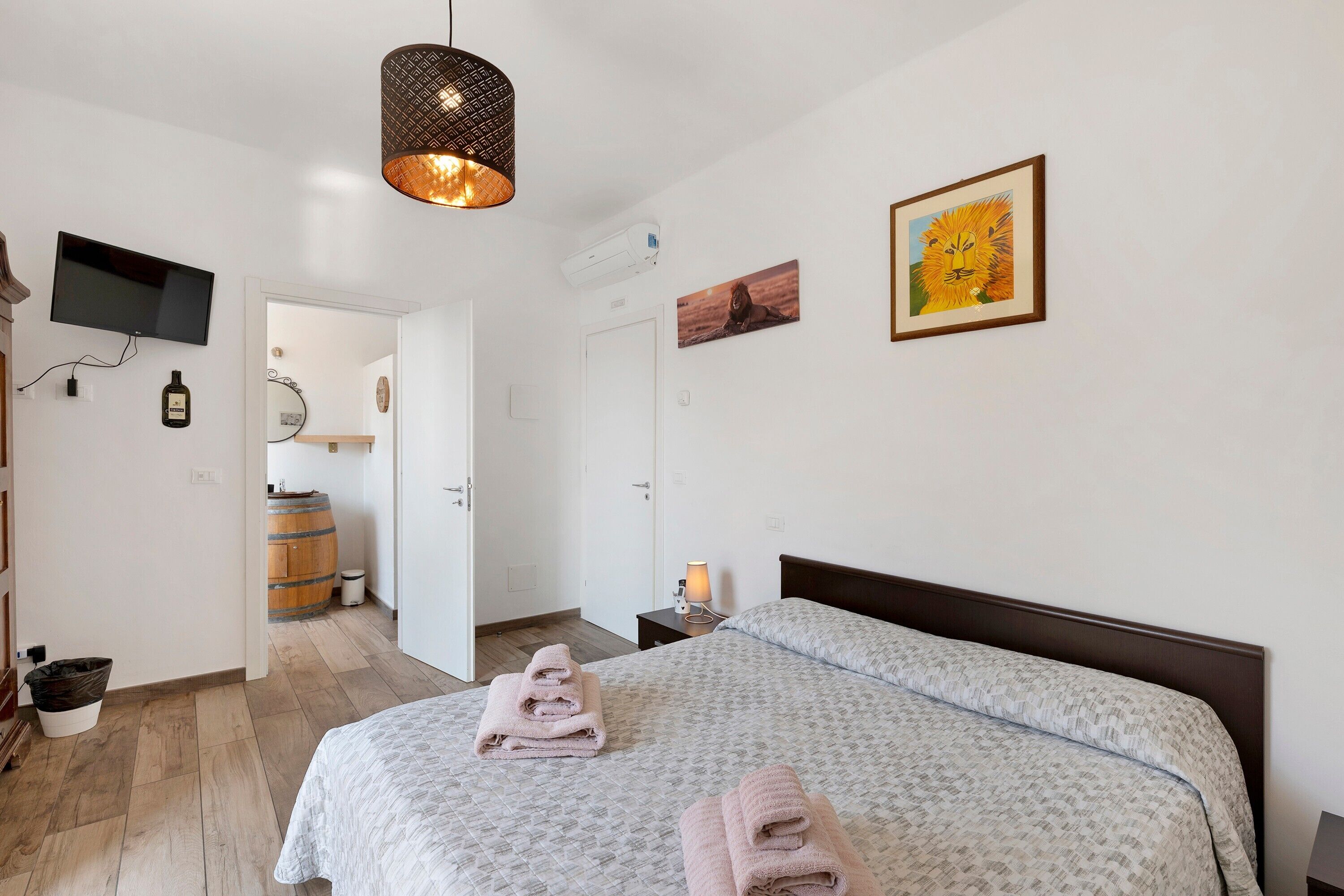 Una camera d'albergo con un letto, una TV, una lampada e un quadro appeso al muro.