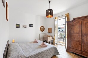 A bedroom with a bed, bedside lamp, wooden wardrobe, and a view of the outside. - Room 'Leone' with Mountain View, Wi-Fi and Air Conditioning (Bastia)