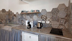 A kitchen with a modern design, featuring a coffee maker, kettle, and a shelf with cups. - Room 'Leone' with Mountain View, Wi-Fi and Air Conditioning (Bastia)