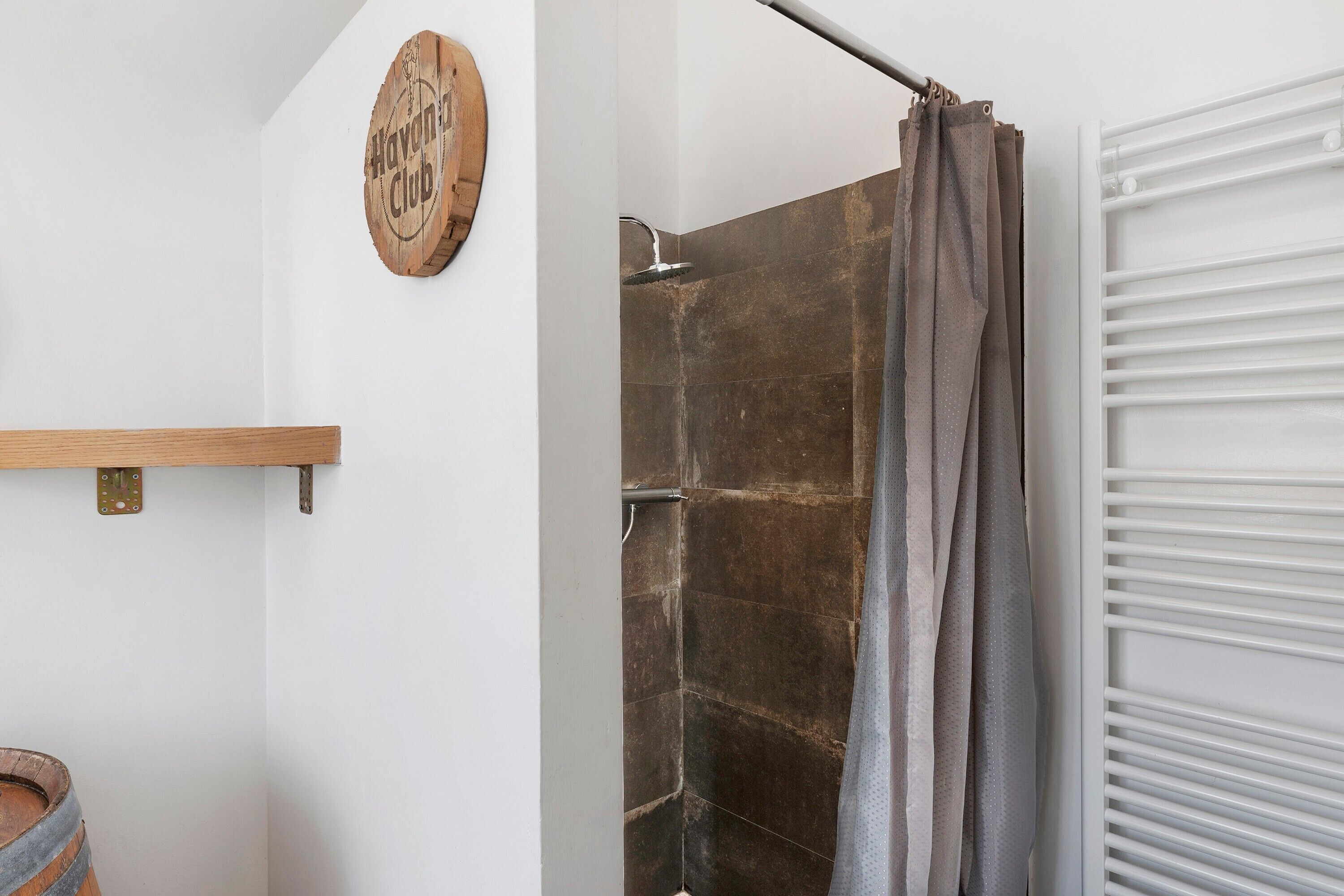A bathroom with a shower, a towel rack, and a wooden sign on the wall.