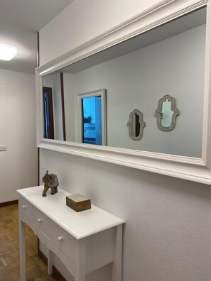 Ein Zimmer mit einem großen Spiegel, einem weißen Schminktisch mit Schubladen und einer kleinen Elefant-Figur.