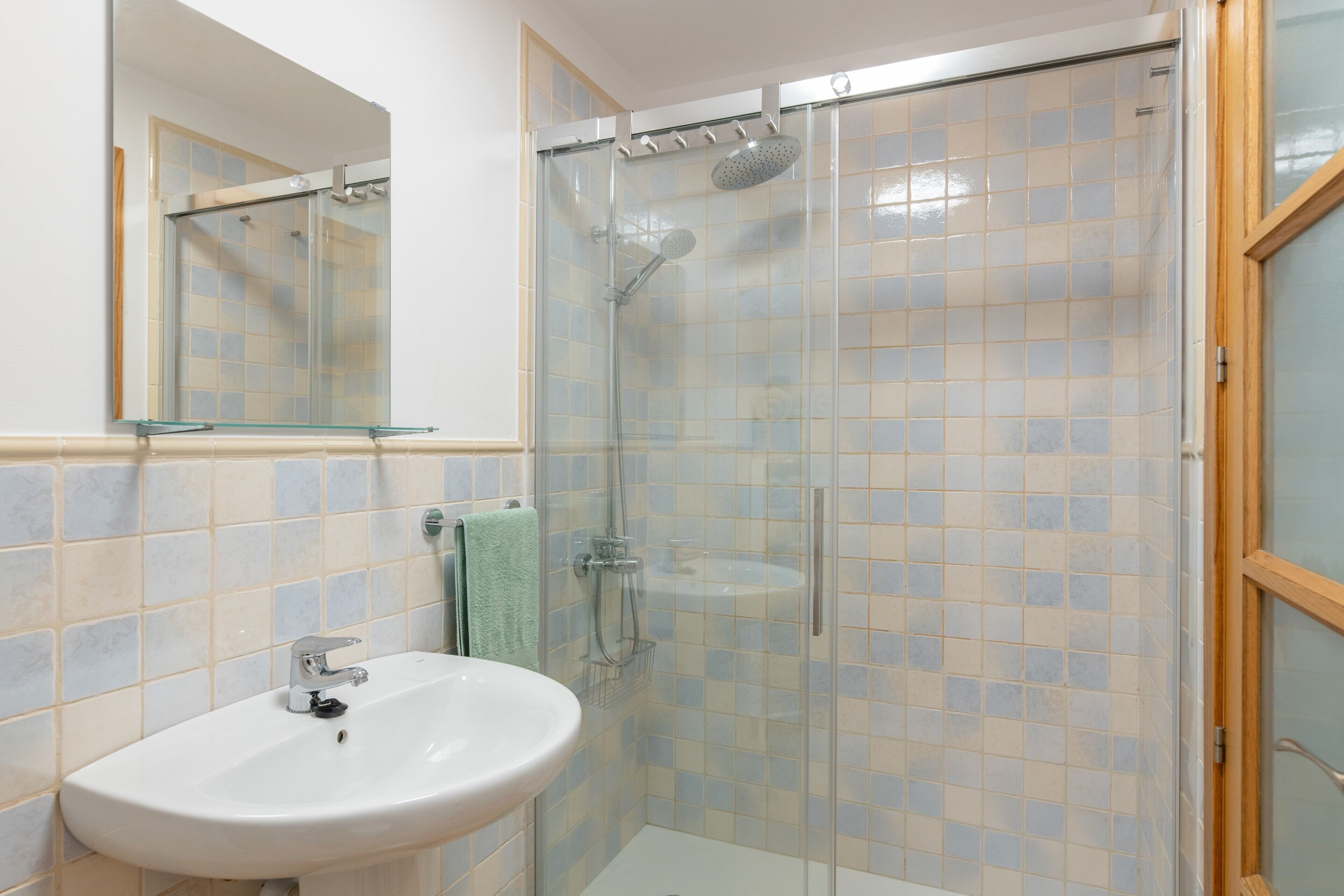 Ein Badezimmer mit einer Duschkabine, einem Waschbecken und einem Spiegel.