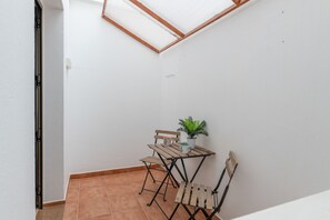 Ein kleiner, abgeschlossener Innenhof mit Tisch und Stühlen, einem Blumentopf und einer Dachfenster.