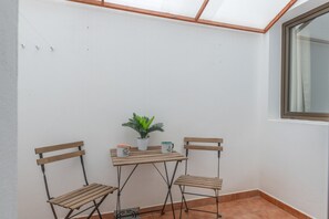 Ein Eckzimmer mit Holztisch, zwei Stühlen, einer Topfpflanze und einem Fenster.