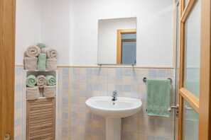 Ein Badezimmer mit Waschbecken, Spiegel und Ablage für Handtücher.