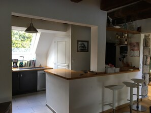 Una cocina con encimera de madera, una lámpara colgante y una ventana, además de una puerta.