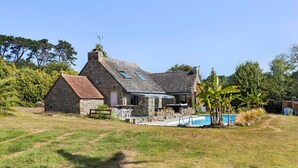 A stone house with a swimming pool, surrounded by grass and trees. - Holiday Home 'Maison Bringwiller Plage 200m' with Private Pool and Terrace (Trégastel)